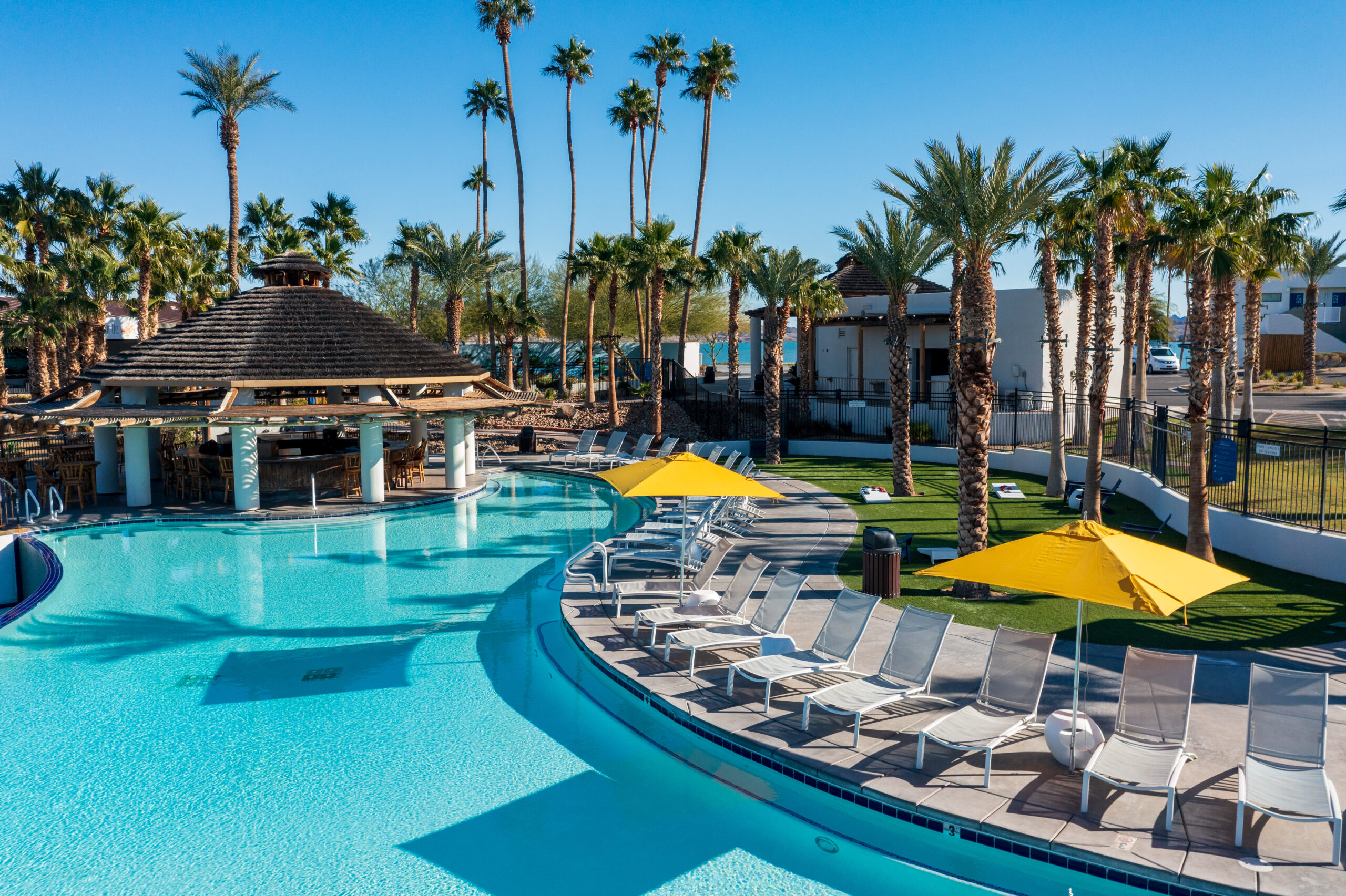 resort pool with chairs along the side and yellow umbrellas